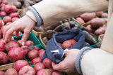 Image of a woman putting red potatoes inside a storm blue mesh produce bag.
